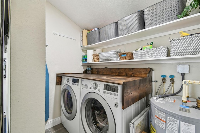 laundry area featuring laundry area, baseboards, a textured ceiling, washing machine and clothes dryer, and water heater
