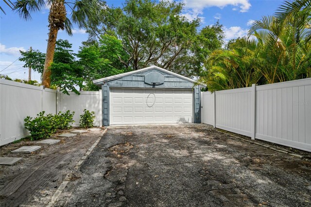 garage featuring fence, a gate, and driveway