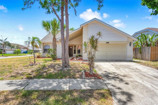 view of front of house with concrete driveway, brick siding, fence, and a garage