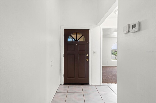 entrance foyer featuring plenty of natural light, baseboards, light tile patterned floors, and light colored carpet
