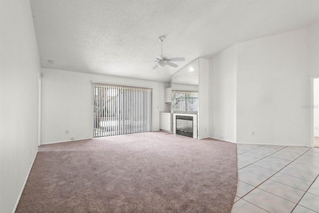 unfurnished living room with baseboards, ceiling fan, a fireplace, and a textured ceiling