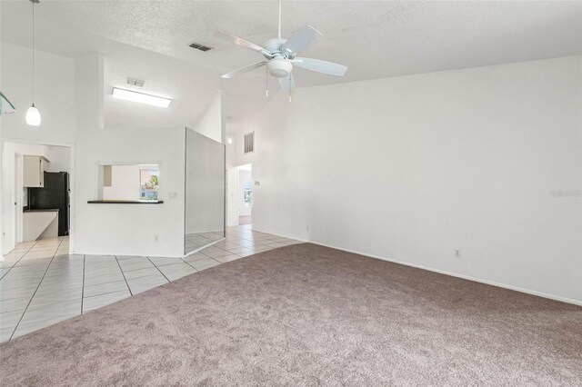 unfurnished living room with a ceiling fan, visible vents, light colored carpet, high vaulted ceiling, and light tile patterned flooring
