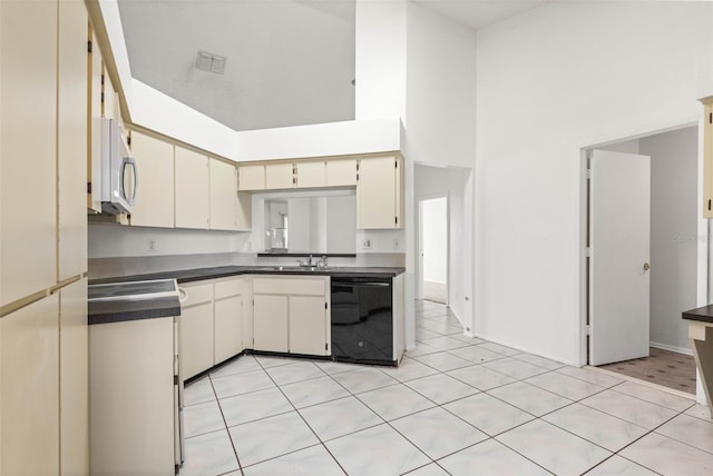 kitchen with dark countertops, a high ceiling, black dishwasher, a sink, and range