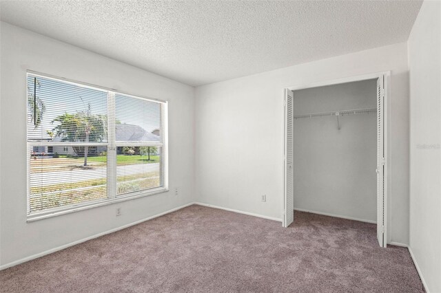 unfurnished bedroom featuring carpet floors, baseboards, a closet, and a textured ceiling