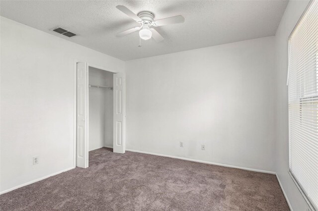 unfurnished bedroom featuring a ceiling fan, a textured ceiling, visible vents, carpet floors, and a closet