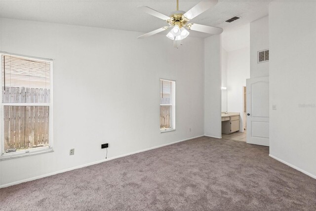 unfurnished bedroom featuring high vaulted ceiling, baseboards, visible vents, and light colored carpet