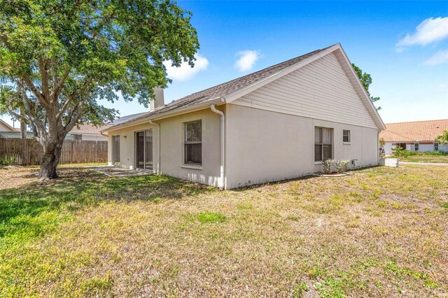 back of house with a lawn, fence, stucco siding, and a chimney