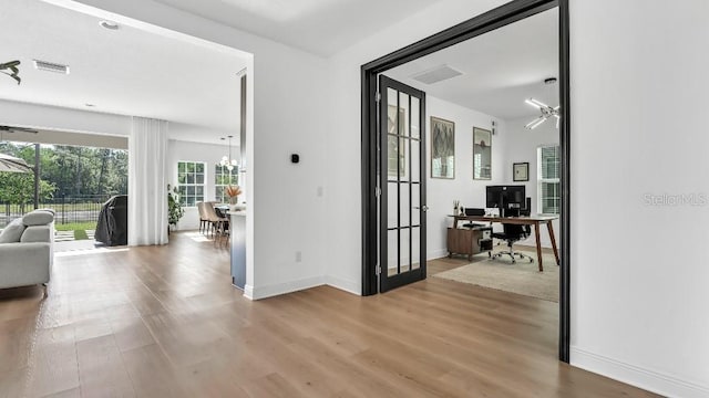 hallway featuring visible vents, light wood-style flooring, baseboards, and a chandelier
