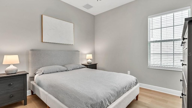 bedroom with baseboards, visible vents, and light wood-style floors