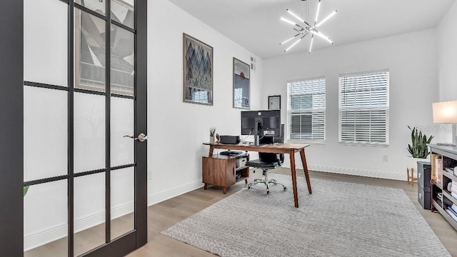 home office with baseboards, a notable chandelier, and wood finished floors