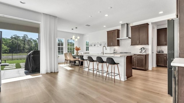 kitchen featuring light countertops, recessed lighting, light wood-style flooring, and wall chimney exhaust hood