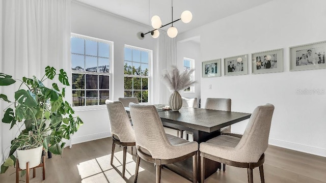 dining room featuring baseboards, wood finished floors, and a notable chandelier