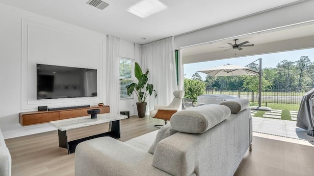 living room with a ceiling fan, visible vents, and wood finished floors