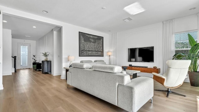 living room with recessed lighting, visible vents, and light wood finished floors