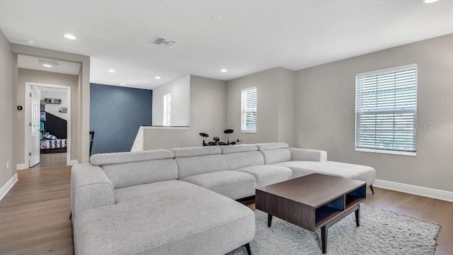 living room featuring light wood-style floors, baseboards, recessed lighting, and visible vents