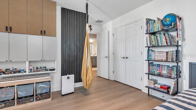 bedroom with baseboards, a closet, light wood-type flooring, and visible vents
