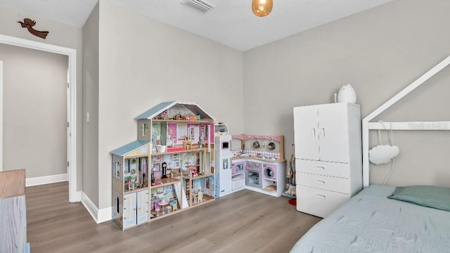 bedroom featuring baseboards, visible vents, and wood finished floors