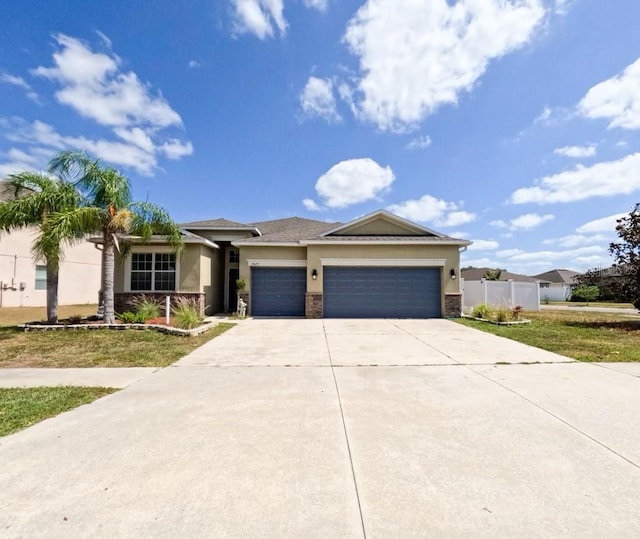 prairie-style home with a garage, fence, stucco siding, and concrete driveway