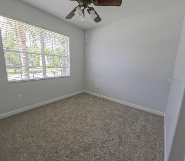 carpeted spare room featuring ceiling fan and baseboards