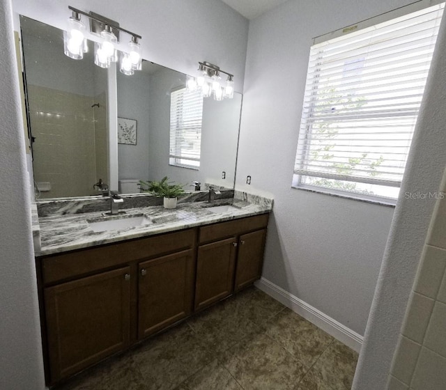 bathroom featuring baseboards, a sink, walk in shower, and toilet