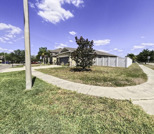 view of front facade with a garage, a front lawn, fence, and driveway