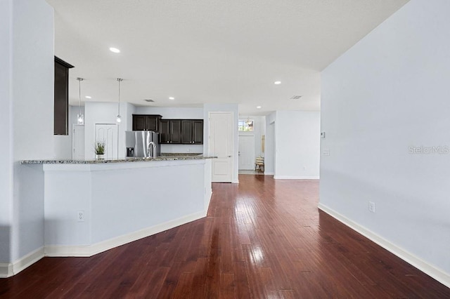 18677 Milton Keynes Ct, Land O Lakes, FL 34638 - kitchen featuring stainless steel fridge with ice dispenser, light stone countertops, dark wood-style flooring, baseboards, and hanging light fixtures