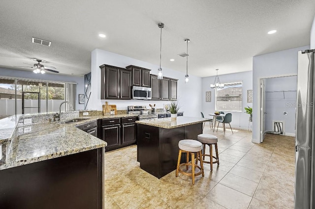 18677 Milton Keynes Ct, Land O Lakes, FL 34638 - kitchen with a sink, stainless steel appliances, a textured ceiling, a breakfast bar area, and light stone counters