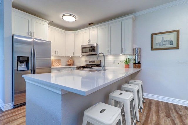 kitchen featuring a sink, appliances with stainless steel finishes, baseboards, and a peninsula