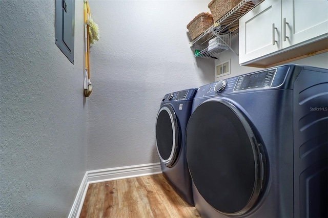 laundry room with washing machine and dryer, cabinet space, baseboards, light wood-style floors, and a textured wall