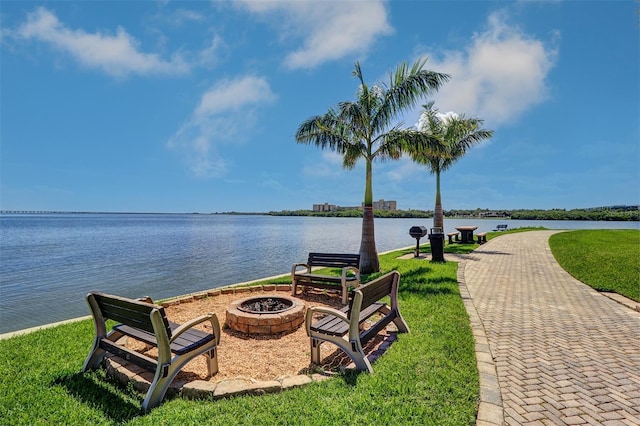 view of community featuring a lawn, a water view, and a fire pit