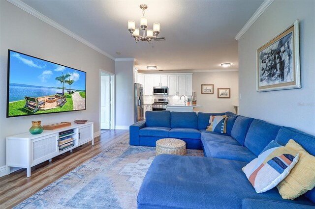 living room featuring baseboards, a notable chandelier, ornamental molding, and light wood-style floors