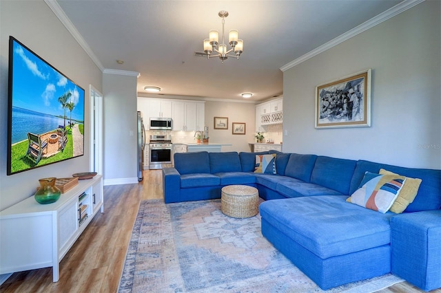 living area featuring crown molding, baseboards, a notable chandelier, and light wood-style flooring