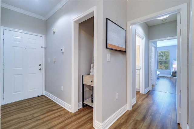 corridor featuring baseboards, ornamental molding, and wood finished floors