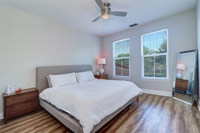 bedroom with baseboards, ceiling fan, wood finished floors, and visible vents