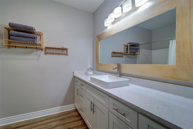 full bath featuring a shower with shower curtain, baseboards, wood finished floors, and vanity