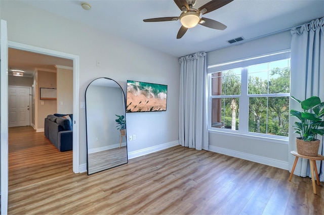 unfurnished room with baseboards, light wood-style floors, ceiling fan, and visible vents