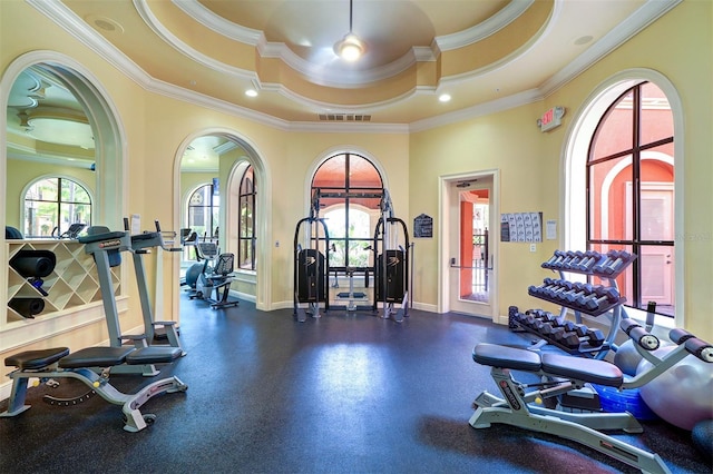 exercise room with baseboards, ornamental molding, a tray ceiling, and visible vents