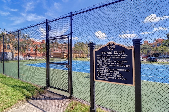 view of tennis court featuring fence and a gate