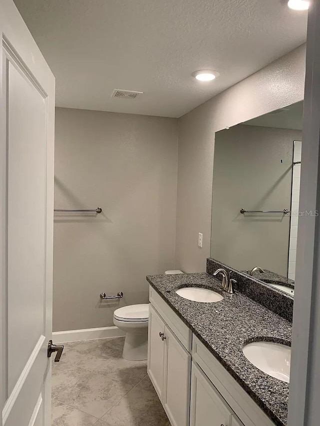 bathroom featuring visible vents, a sink, double vanity, and toilet