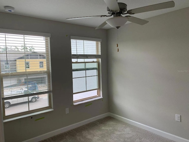 unfurnished room with baseboards, plenty of natural light, a ceiling fan, and carpet flooring