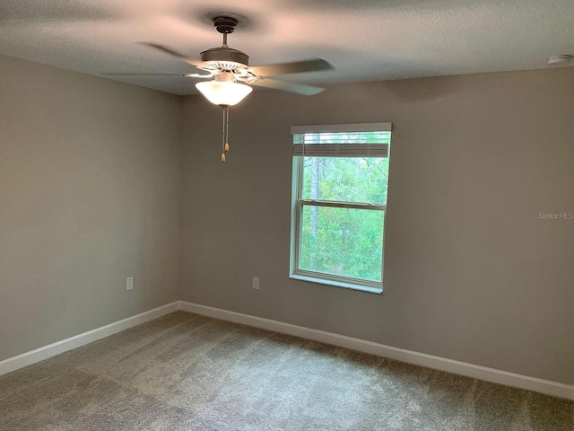 spare room with baseboards, a ceiling fan, a textured ceiling, and light carpet