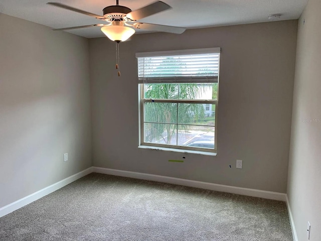 carpeted spare room featuring baseboards and ceiling fan