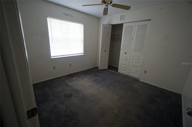 unfurnished bedroom featuring a closet, a textured ceiling, dark colored carpet, ceiling fan, and baseboards