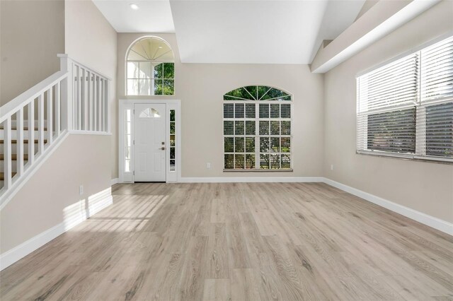 entryway with plenty of natural light, stairs, baseboards, and wood finished floors