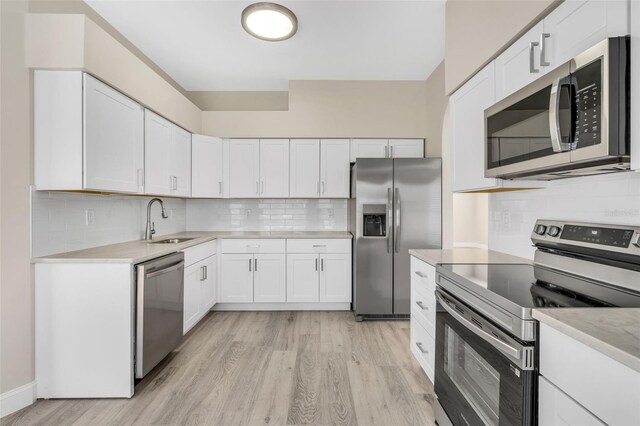 kitchen featuring decorative backsplash, light countertops, a sink, light wood finished floors, and stainless steel appliances