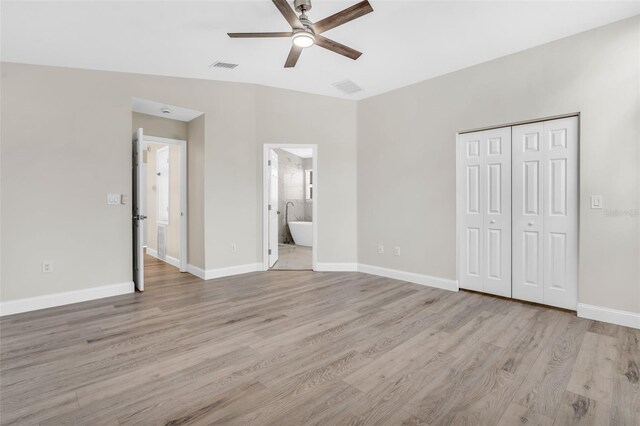 unfurnished bedroom with visible vents, light wood-style flooring, and a closet
