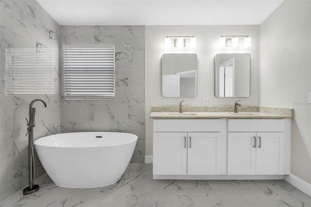 full bath with double vanity, a soaking tub, a sink, and marble finish floor