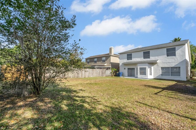 rear view of house featuring fence, stucco siding, a yard, and cooling unit