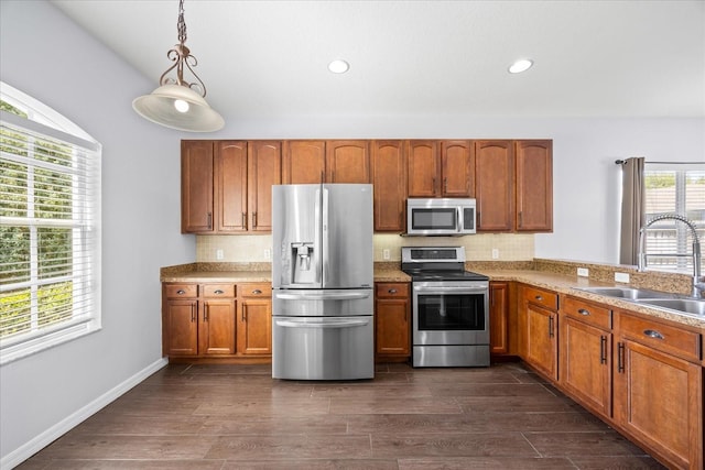 kitchen with brown cabinets, decorative backsplash, appliances with stainless steel finishes, and a sink