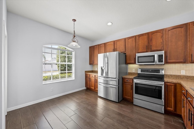 kitchen featuring baseboards, dark wood-style flooring, hanging light fixtures, decorative backsplash, and stainless steel appliances